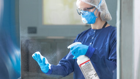 Technician cleaning a cleanroom with Ecolab product